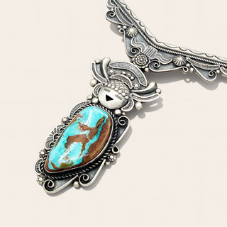Silver necklace with a large pendant featuring a turquoise stone and a depiction of a deer.