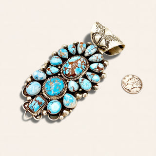 Turquoise stone pendant with silver setting on a beige background