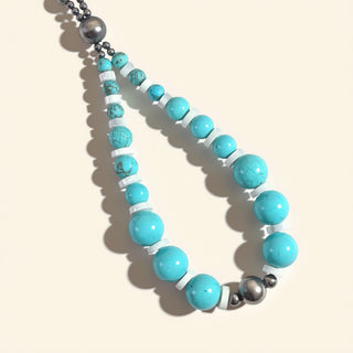 Necklace with turquoise, white, and silver beads on a beige background