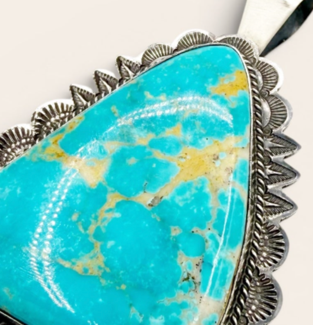 Turquoise stone pendant with silver border on a white background