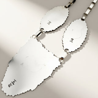 Silver necklace with scalloped-edged pendants on a light gray background