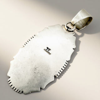 A sterling silver pendant with a textured, hand-hammered finish and scalloped edges, featuring a TF Shining logo, shown on a neutral light beige background.