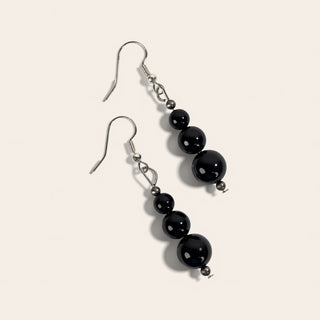 Pair of black beaded earrings on a light beige background
