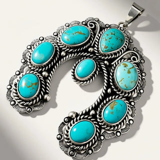 A silver-toned Southwestern-style pendant necklace featuring seven oval turquoise stones set in ornate filigree and rope-textured silver settings, displayed on a light gray background with soft diagonal shadows.