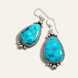 pair of turquoise pebble earrings on a beige background