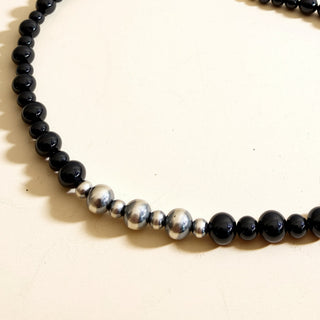 Necklace with black beads and silver accents on a white background
