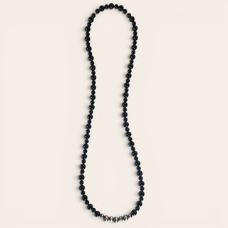 Black beaded necklace on a light beige background