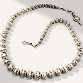 silver beaded necklace on a beige background