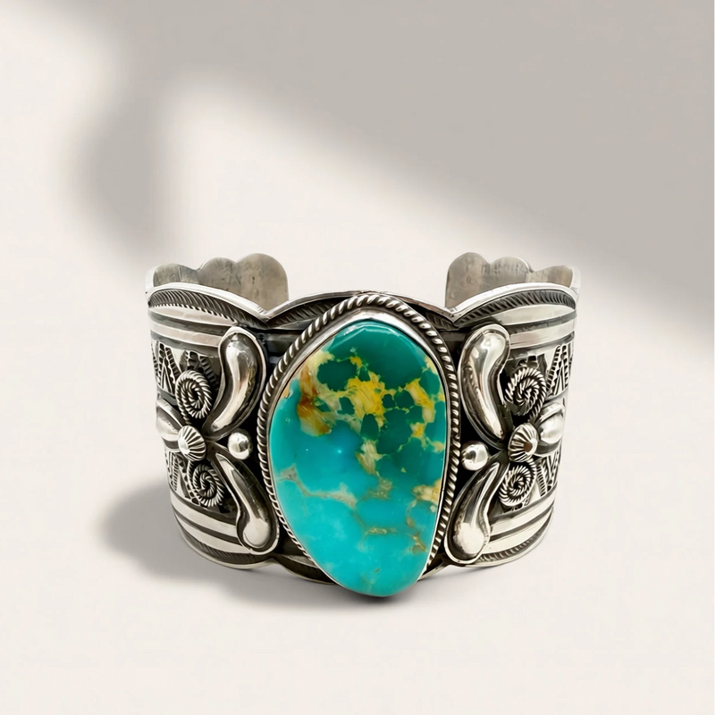Silver cuff bracelet with a turquoise stone on a light gray background