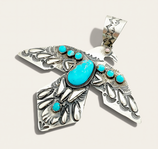 Silver Bird Pendant with Turquoise stones on a cream background
