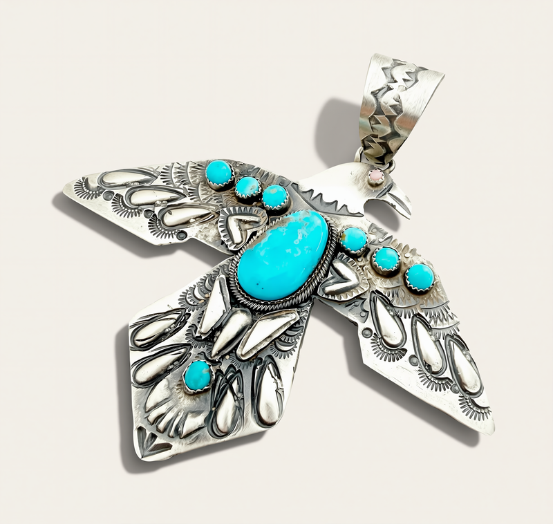 Silver Bird Pendant with Turquoise stones on a cream background