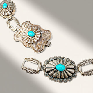 A silver-toned Southwestern-style concho bracelet featuring turquoise stone accents, displayed on a light gray background with soft diagonal shadows.