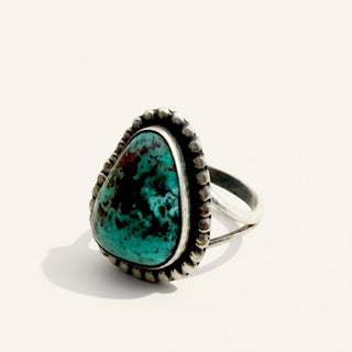 silver ring with triangle turquoise stone on a beige background