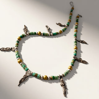 Beaded necklace with green, yellow, and white beads on a light gray background
