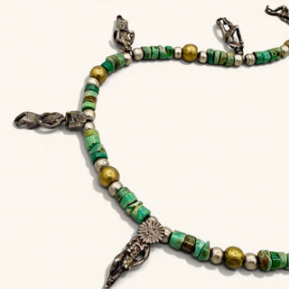 Necklace with green and gold beads and silver clasps on a white background