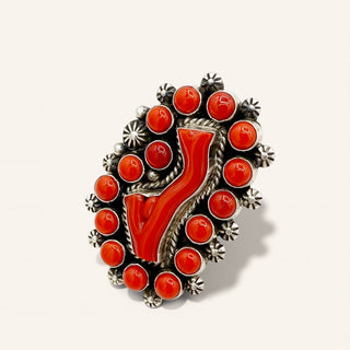 Decorative ring with red stones and silver accents on a white background