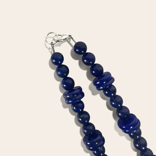 Blue beaded necklace with silver clasp on a white background