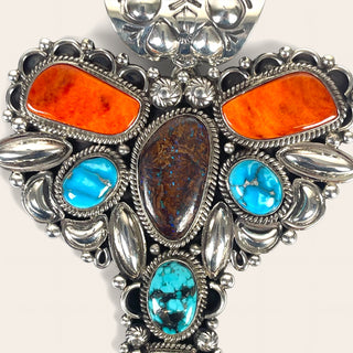 Silver jewelry piece with orange and blue stones on a white background