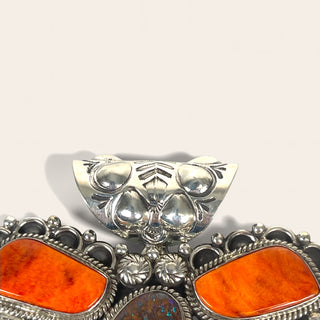 Silver and orange brooch on a white background