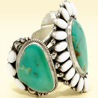 Silver cuff with turquoise stones and white beads on a beige background