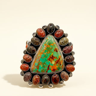 Cuff with a large triangular turquoise stone and smaller colored stones on a beige background