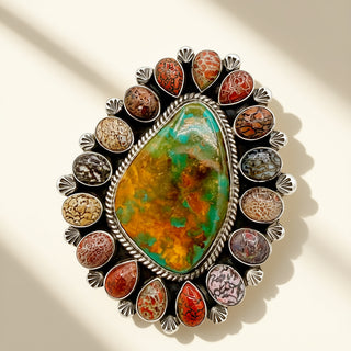 Stylish brooch with a large central stone and smaller stones around on a neutral background