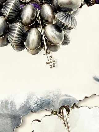 Close-up of a silver brooch with 'Sterling 25' marking on a white background