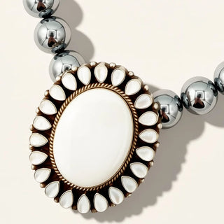 silver beaded jewelry with white pendant on a beige background