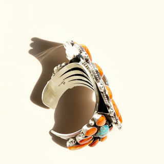 Silver cuff with orange and turquoise stones on a white background