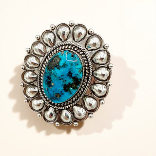 Silver ring with blue stone against a beige background