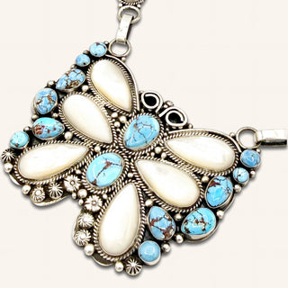 Silver butterfly pendant with turquoise stones on a beige background