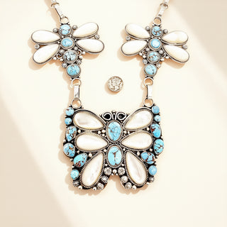 Butterfly-shaped necklace with white and turquoise stones on a beige background