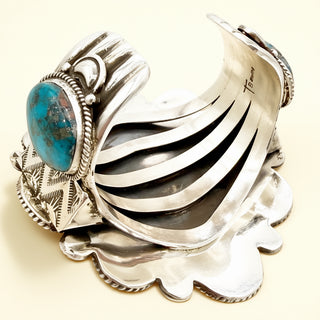 Silver cuff bracelet with turquoise stone on a beige background