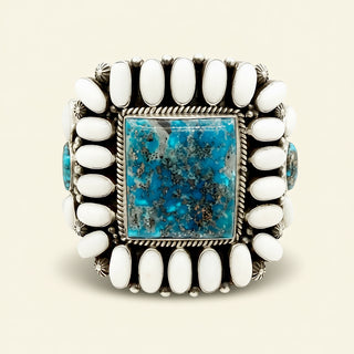 Cuff with turquoise stone and white beads on a beige background