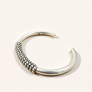 Silver bangle with textured design on a light gray background