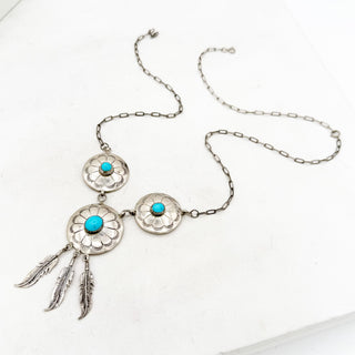 Silver necklace with turquoise stones and feather pendants on a white background