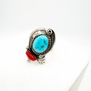 Silver ring with turquoise stone and red accent on a white background