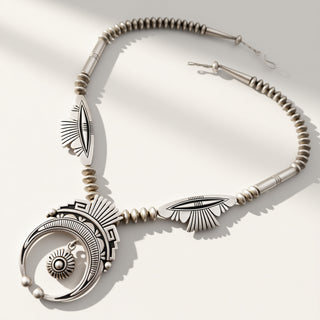 Silver necklace with intricate designs on a white background