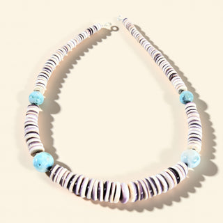 Necklace with striped beads and blue accents on a beige background