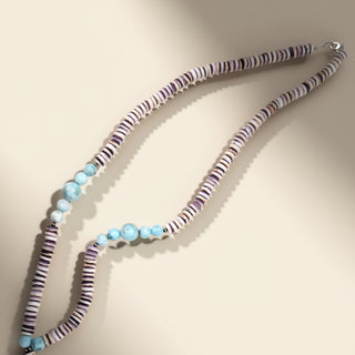 Necklace with striped beads and blue accents on a beige background