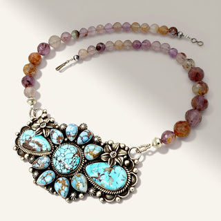 Necklace with turquoise pendant and multicolored beads on a white background