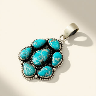 Turquoise pendant with silver setting on a beige background