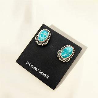 Pair of turquoise earrings on a black card with 'Sterling Silver' text.