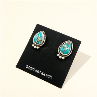 Pair of turquoise and silver earrings on a black card labeled 'Sterling Silver'.