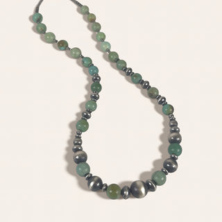 Necklace with green and gray beads on a light background