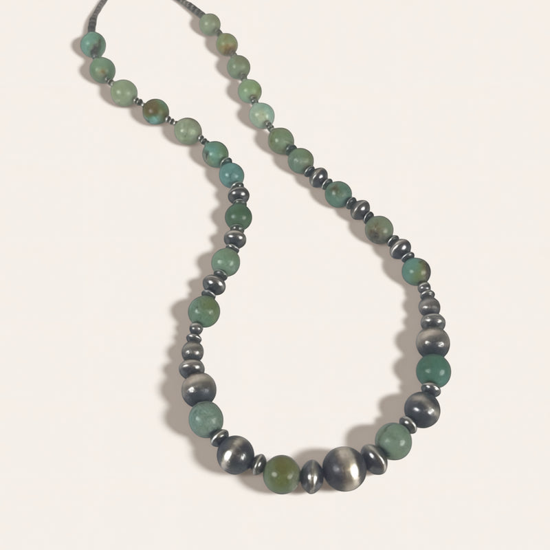 Necklace with green and gray beads on a light background