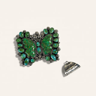 Green stone brooch with silver detailing on a white background